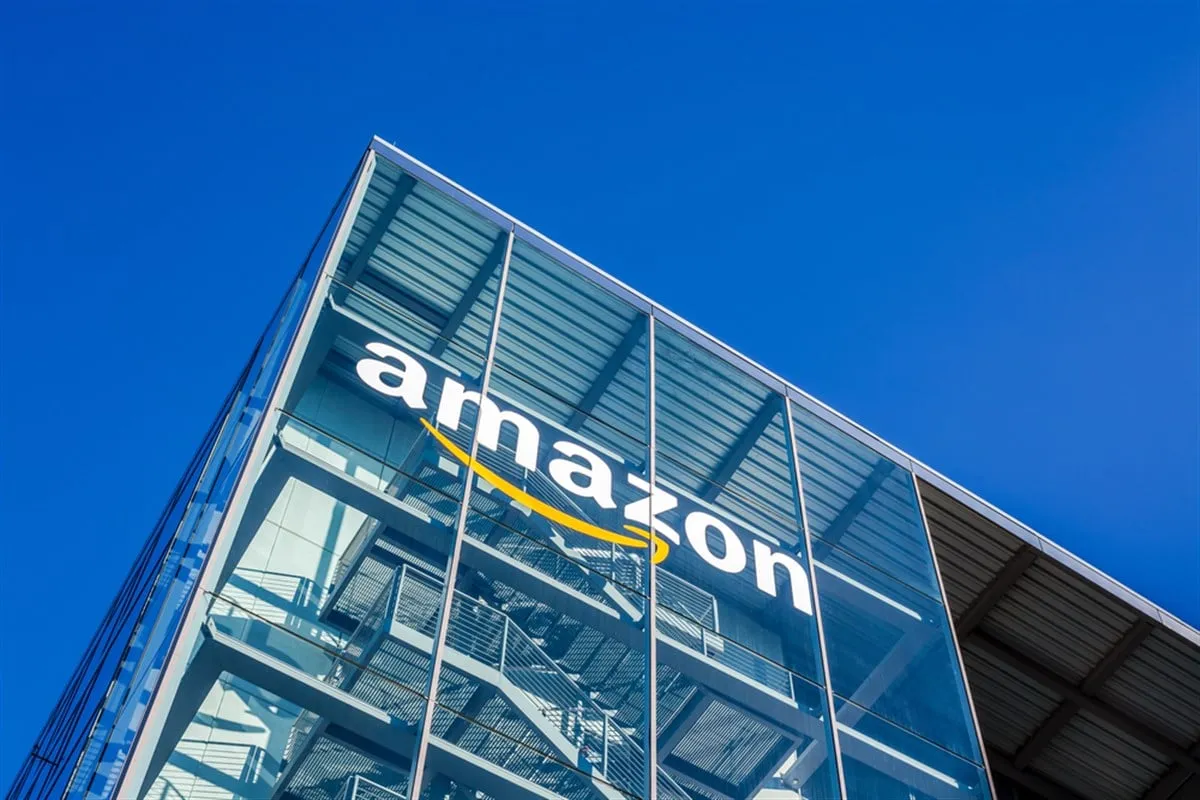 Amazon logo on a glass office building against blue sky